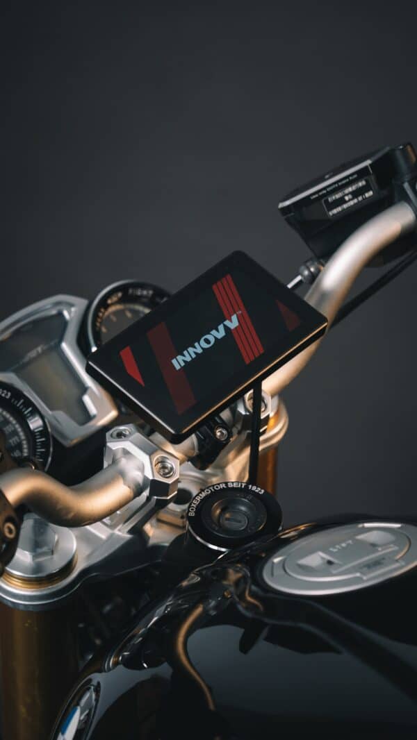 Close-up of a motorcycle handlebar with an attached digital display screen, showing the brand logo "INNOVV," flanked by the bike's high-end instrumentation and control levers.